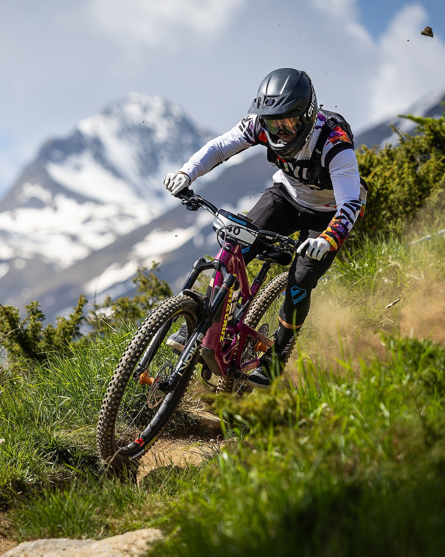 Person riding a mountain bike on a trail with mountains in the background