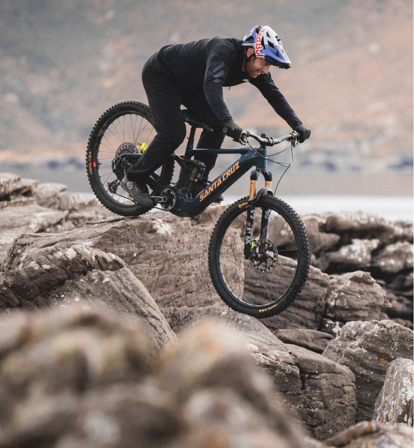 Person riding a mountain bike on rocky terrain with a scenic background