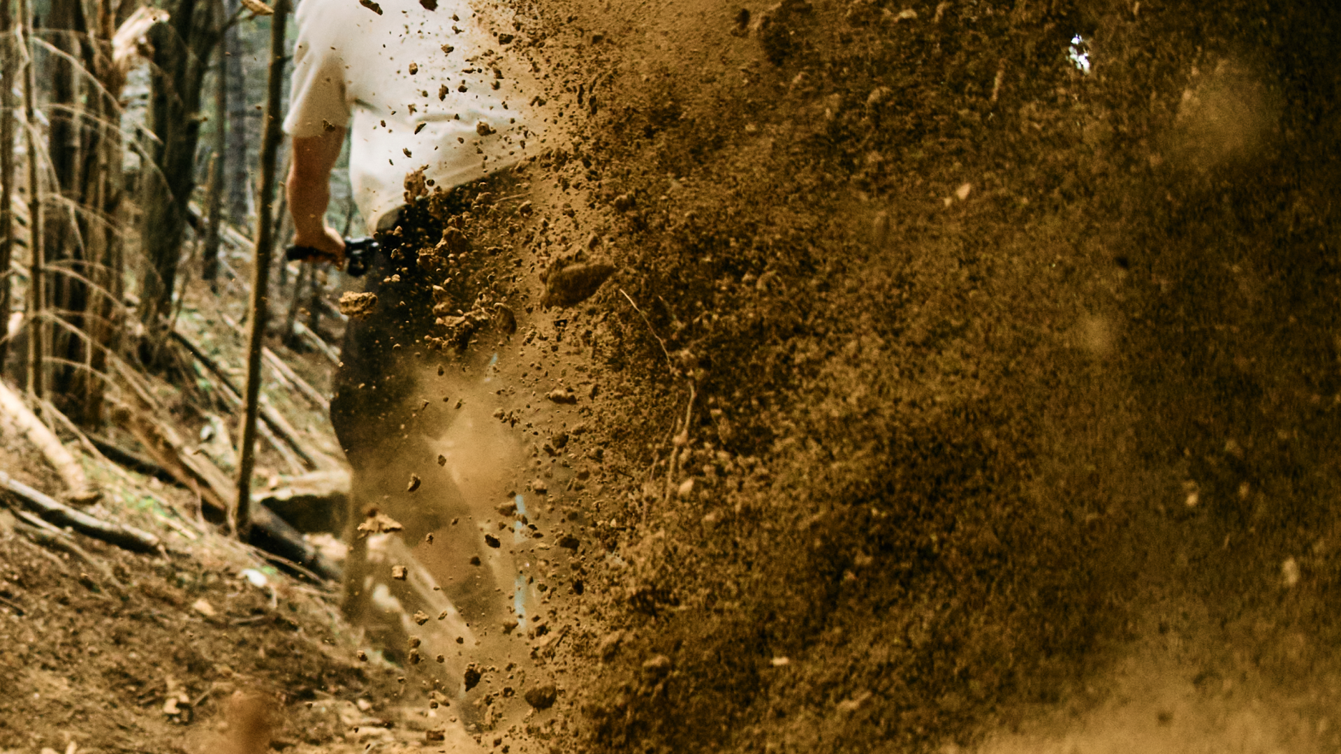 Person walking through a muddy forest path with a stick