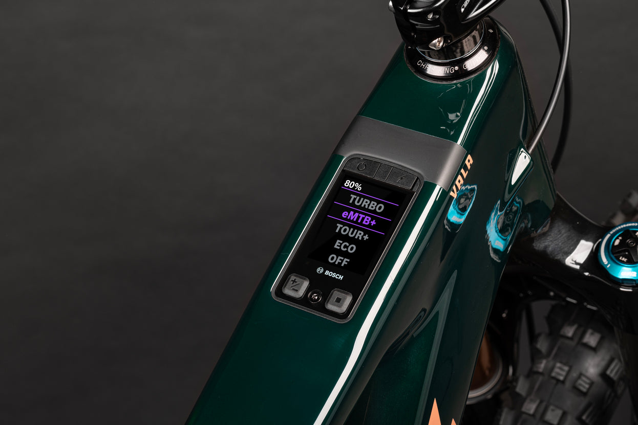 Close-up of a bicycle's digital display panel with control buttons on a dark background