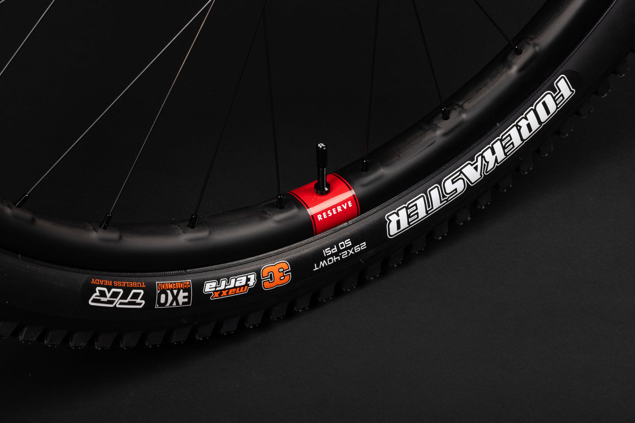 A Carbon bicycle rim, tubeless valve, and Maxxis Forekaster tire