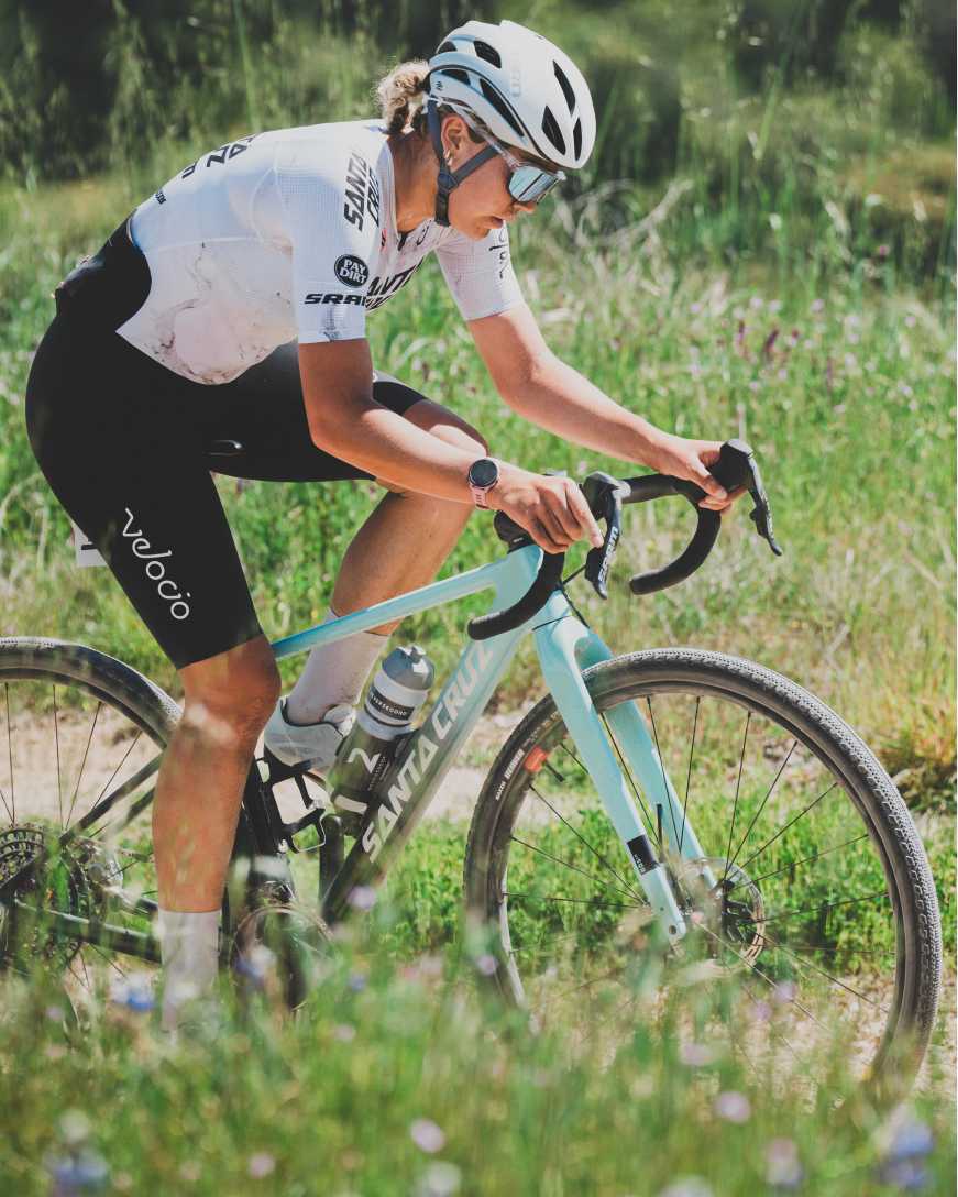 Cyclist riding a teal bicycle in a grassy field with wildflowers